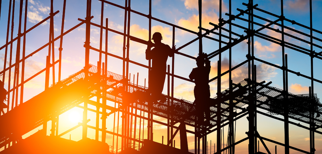 Two silhouetted construction workers standing on scaffolding at a building site during sunset, with a dramatic orange-to-blue sky and metal framework creating a striking industrial scene
