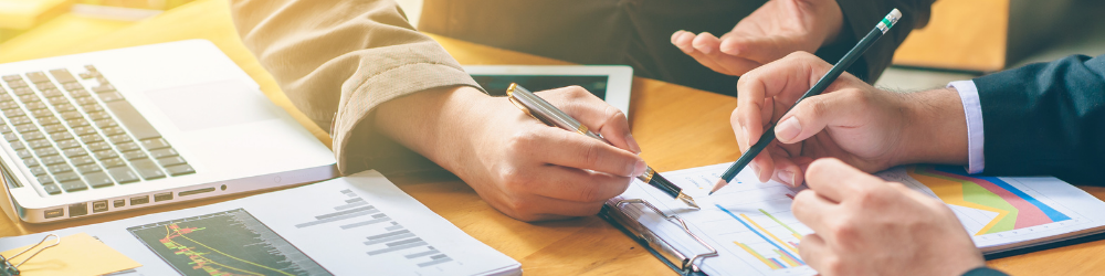 Sydney business professionals reviewing financial charts and legal documents with laptop data, highlighting the importance of commercial litigation support for SMEs.