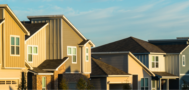 Row of modern suburban houses with varied architectural styles and neutral tones like beige, gray, and blue, under a clear sky with light clouds — representing residential property, real estate listings, and suburban living.